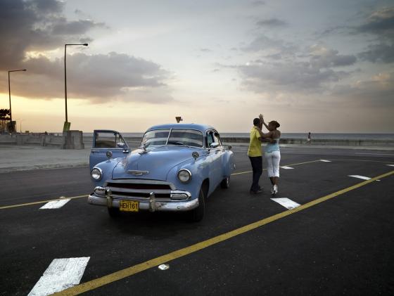 Fotografa de Jos Mara Mellado a una pareja bailando junto a Chevy azul, en Cuba.