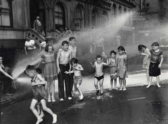 Fotografía en blanco y negro de unos niños refrescándose en la calle 