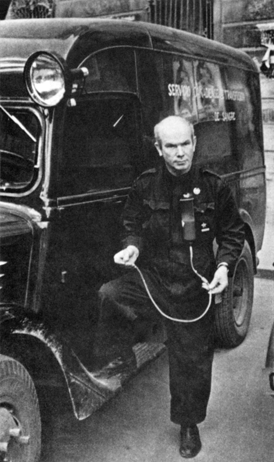 Fotografa en blanco y negro, tomada por G. Karpathi, de Norman Bethune posando junto a la ambulancia que us durante su estancia en Espaa en 1937